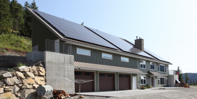 Photo of the front view of a new home with 3 car garage and solar paneled roof.