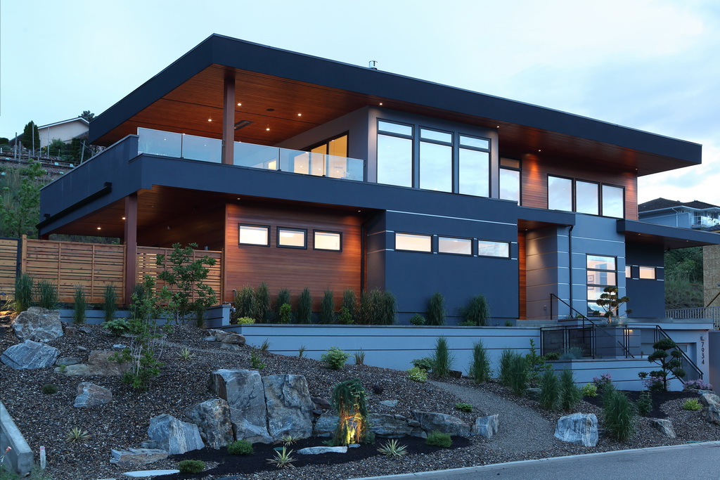Photo of the front view of a new home at dusk, with interior lights on.