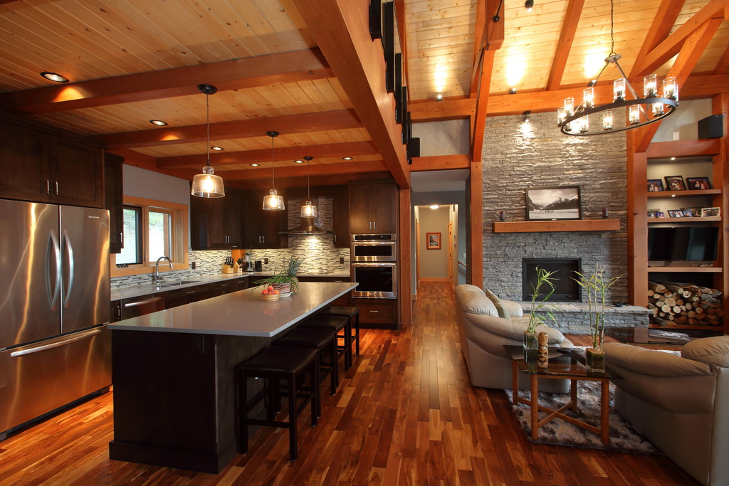 Photo of kitchen and living room in beautiful timber frame home, with cultured stone fireplace.