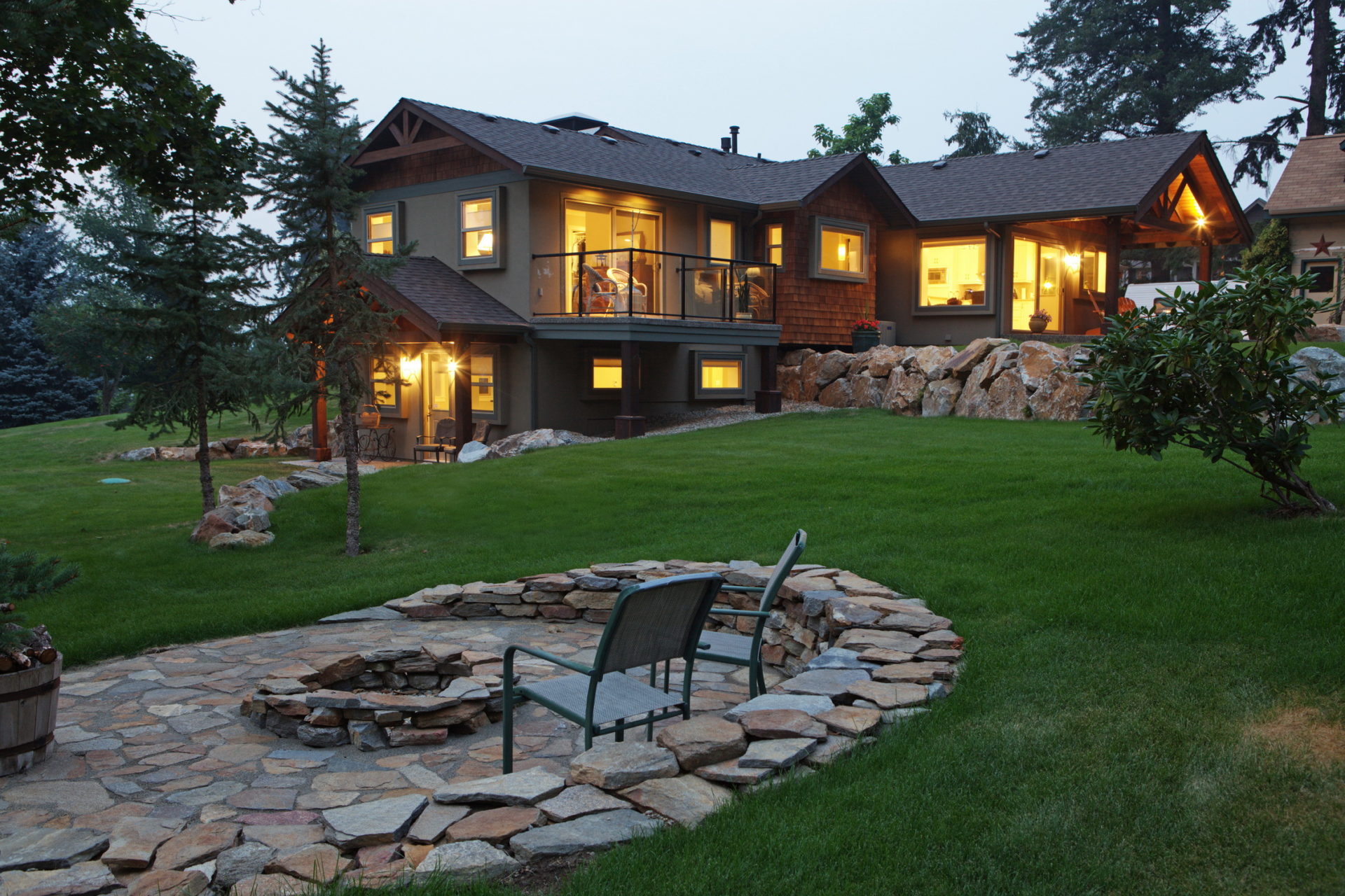 Photo of side view of timber frame home and beautiful slate rock fire pit and sitting area.