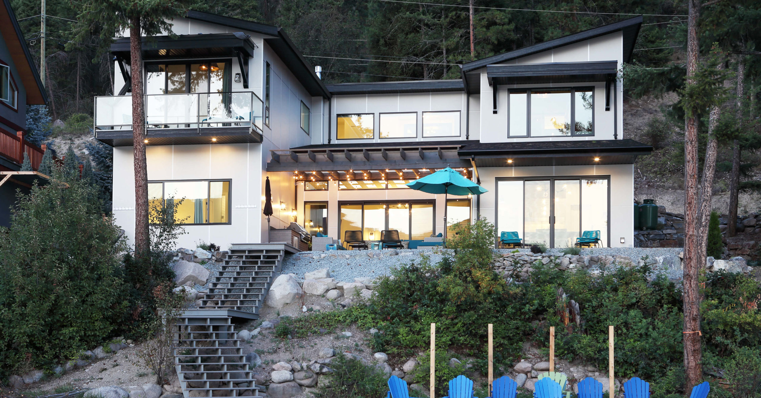 Evening view of home on beachside, with blue patio chairs out front.