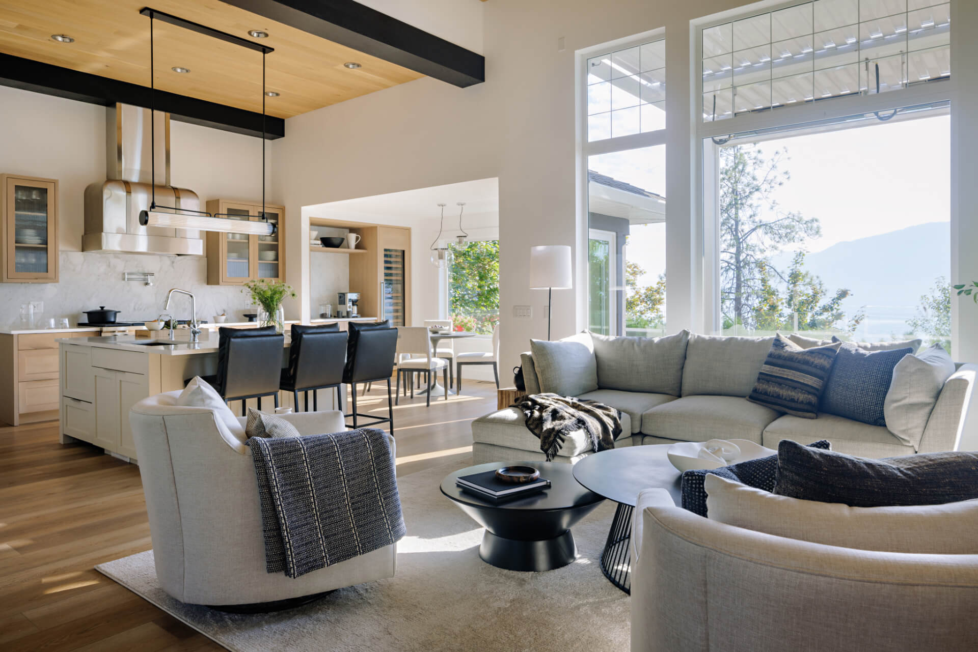 Photo of beautiful renovation of contemporary kitchen, living room and dining room, with large windows overlooking lake.