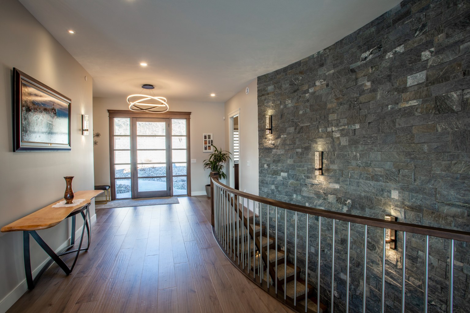 Photo of sunlit glass door front entry with cultured stone accent stairwell wall.