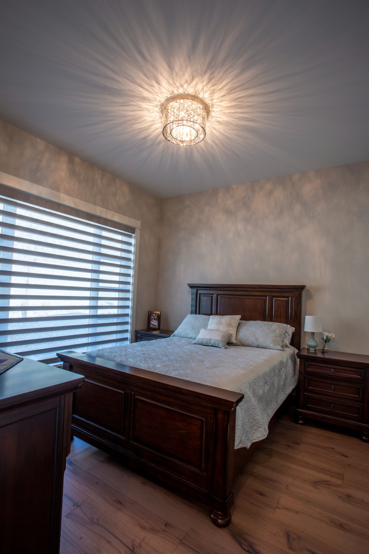 Photo of spare bedroom with overhead crystal light fixture.