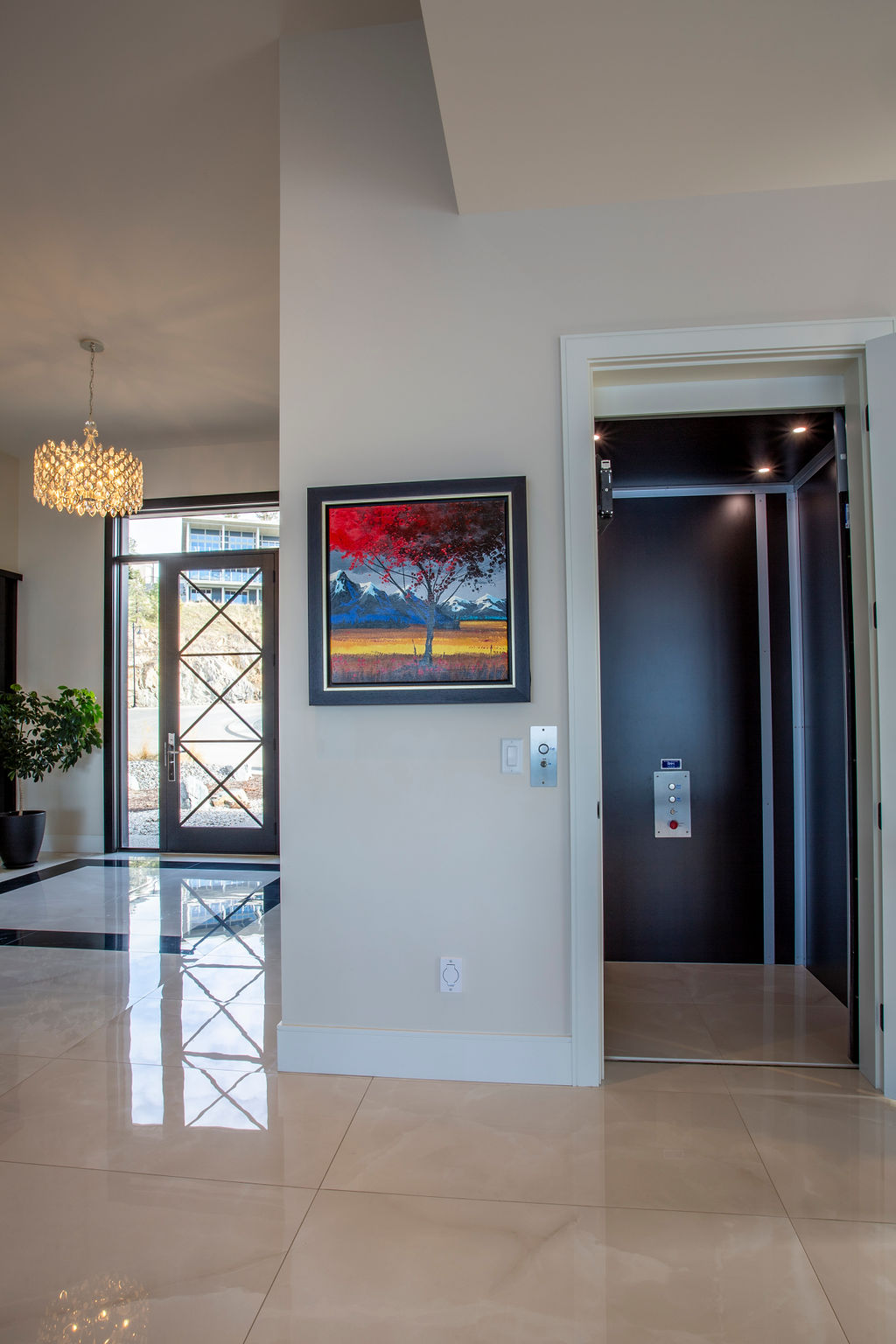 Photo of glass door in front entry with bright colored painting of tree in the fall.